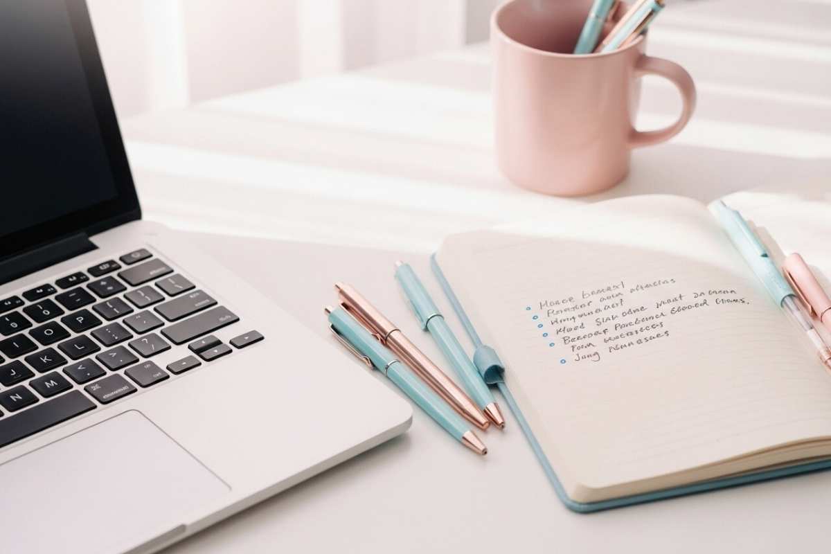 ノートとノートパソコンが置かれた明るいデスク